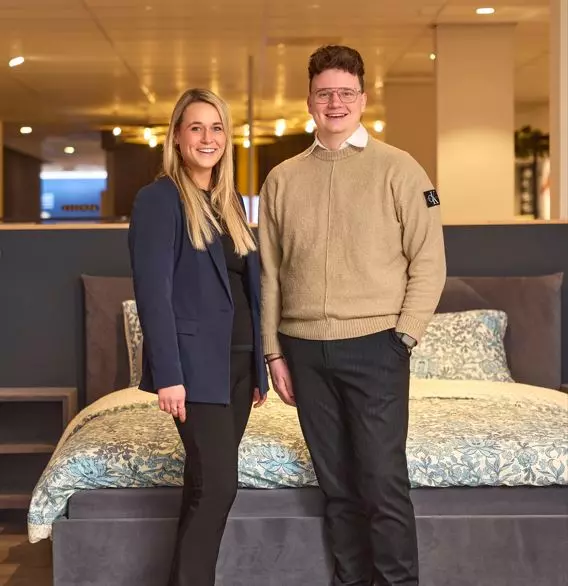 Een acteur op een stoel wacht terwijl een cameraman en iemand van productie aan het praten zijn.